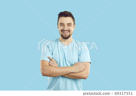 Happy handsome young man in a blue T shirt standing with his arms crossed and smiling Happy handsome young man in a blue T shirt standing with his arms crossed and smiling 89317351