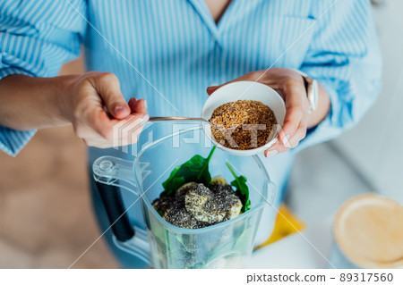 Close up woman adding flex seeds during making smoothie on the kitchen. Superfood supplement. Healthy detox vegan diet. Healthy dieting eating, weight loss program. Selective focus. Copy space 89317560