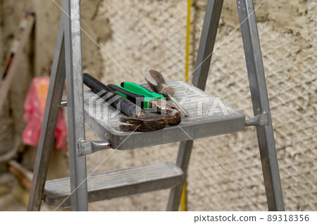 Set of three construction tools on a ladder hammer, pliers and screwdriver. 89318356