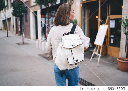 Unrecognizable trendy woman with backpack strolling on street 89318505