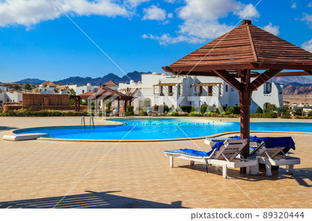 Chaise longues near a swimming pool. Concept of spa, rest, relaxation, holidays, resort Chaise longues near a swimming pool. Concept of spa, rest, relaxation, holidays, resort 89320444