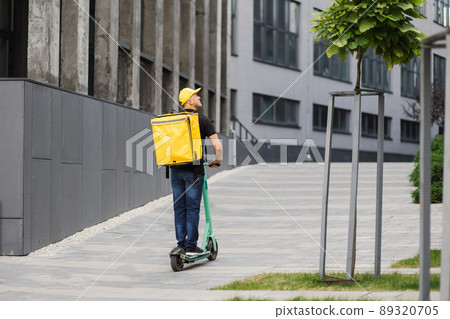 Delivery man of takeaway on scooter with isothermal food case box. Delivery man of takeaway on scooter with isothermal food case box. 89320705