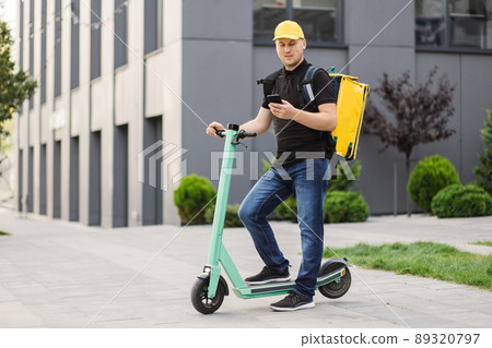 Food delivery man with thermo backpack holding mobile phone waiting next order Food delivery man with thermo backpack holding mobile phone waiting next order 89320797