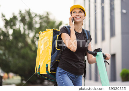 Delivery woman in black t-shirt delivering order to customer. Delivery woman in black t-shirt delivering order to customer. 89320835