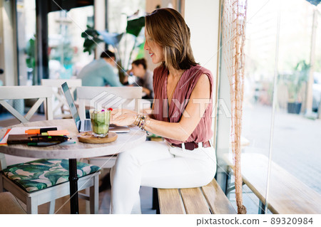 Content woman browsing laptop in cafe 89320984