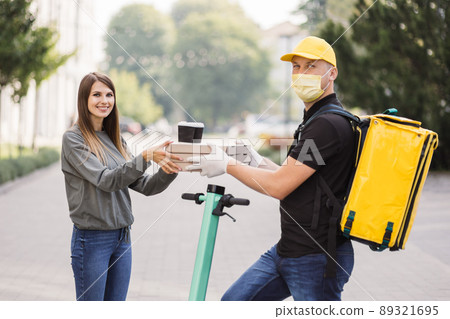 Attractive young delivery guy holding boxes with hot pizza and two cups of hot drink coffee. Attractive young delivery guy holding boxes with hot pizza and two cups of hot drink coffee. 89321695