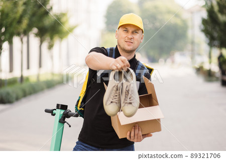Courier opens the box looking at camera and pulls out his sneakers. 89321706