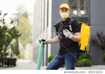 Delivery guy wearing facial mask working during covid-19 pandemic with backpack. 89321814