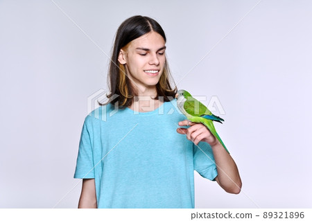 Young male with domestic green Quaker parrot on light studio background Young male with domestic green Quaker parrot on light studio background 89321896
