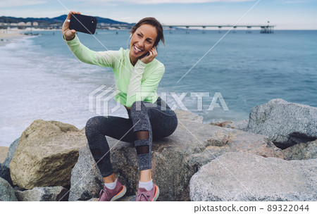 Happy fit girl in earphones shooting influence video vlog 89322044