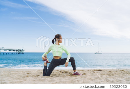 Flexible mature female doing yoga exercises on beach 89322080
