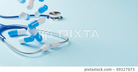 Top view of medical stethoscope and pill capsule falling on light blue background 89327873