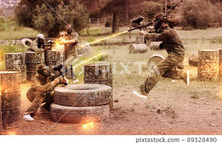 Two active opposing teams with guns playing paintball Two active opposing teams with guns playing paintball 89328490