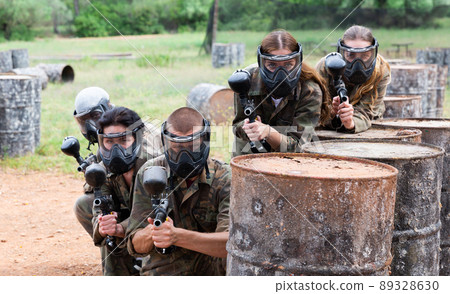 Group of paintball players aiming and shooting with guns Group of paintball players aiming and shooting with guns 89328630