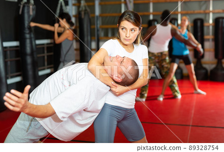 Latino woman is training with man on self-defense course in gym Latino woman is training with man on self-defense course in gym 89328754