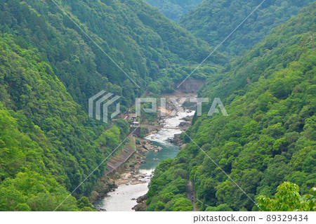 Looking at Hozukyo in the summer from Saga-Arashiyama / Rokucho Pass, a trolley train heading for Arashiyama Station departed. 89329434