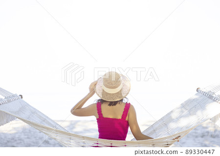 Asian woman relaxing in the hammock on tropical beach, njoy her freedom and fresh air, wearing stylish hat and clothes. Happy smiling tourist in tropics in travel vacation 89330447