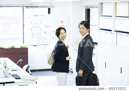 Two office workers, male and female, turn around, smile, look at the camera Two office workers, male and female, turn around, smile, look at the camera 89331052