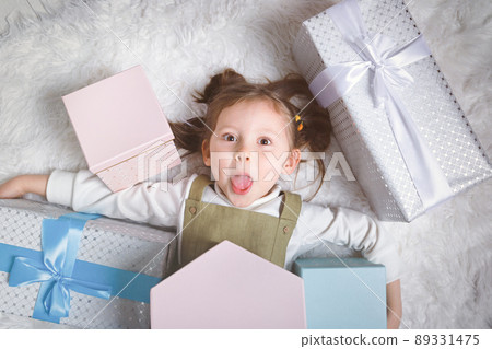 Happy girl sticks out her tongue because she received a lot of New Year's gifts Happy girl sticks out her tongue because she received a lot of New Year's gifts 89331475