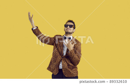 Funny black man in a leopard suit and cool sunglasses dancing isolated on a colour background 89332610