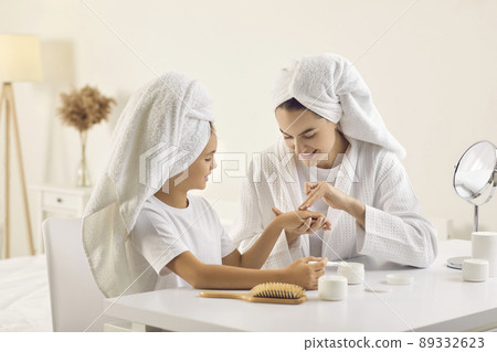 Happy beautiful mom and her child in white towels doing skin care routine together 89332623