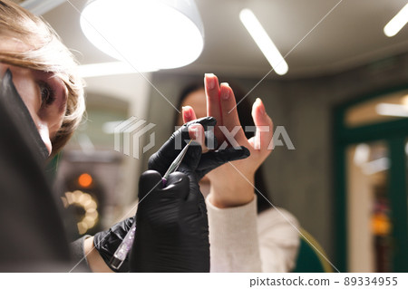 Cuticle care during a manicure process in a nail salon. Cuticle care during a manicure process in a nail salon. 89334955
