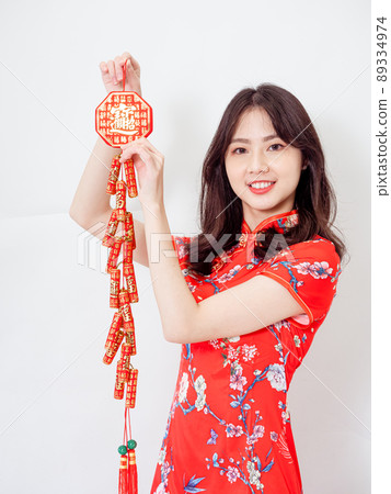 Young asian woman wearing traditional cheongsam qipao dress hold Chinese festival couplet to celebrate new year with word meaning good fortune on white background. Young asian woman wearing traditional cheongsam qipao dress hold Chinese festival couplet to celebrate new year with word meaning good fortune on white background. 89334974