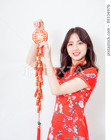 Young asian woman wearing traditional cheongsam qipao dress hold Chinese festival couplet to celebrate new year with word meaning good fortune on white background. Young asian woman wearing traditional cheongsam qipao dress hold Chinese festival couplet to celebrate new year with word meaning good fortune on white background. 89334976