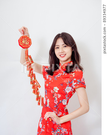 Young asian woman wearing traditional cheongsam qipao dress hold Chinese festival couplet to celebrate new year with word meaning good fortune on white background. 89334977