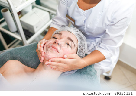 Doctor beautician makes cosmetic facial massage. Woman relaxes on a cosmetic chair.. 89335131