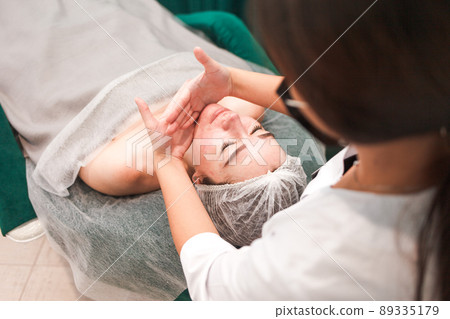 Doctor beautician doing cosmetological massage of the chin for her patient 89335179