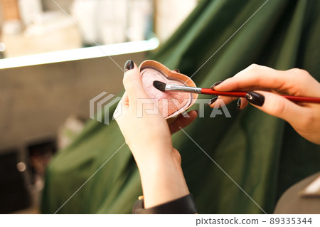 Makeup artist takes a blush with a brush straight from the palette. 89335344