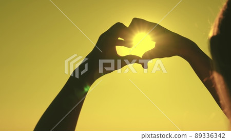 silhouette of the heart in the rays of the sun. make heart symbol with hands. valentine. love sign. freedom of travel. happiness of a woman's dream. heart against the sky. declaration love to person. 89336342