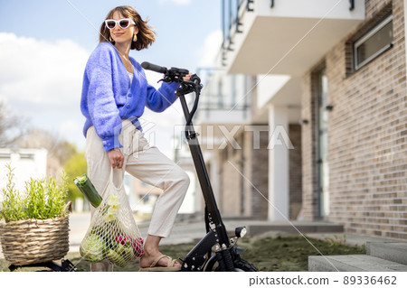 Woman going home with fresh vegetables on electrical scooter Woman going home with fresh vegetables on electrical scooter 89336462