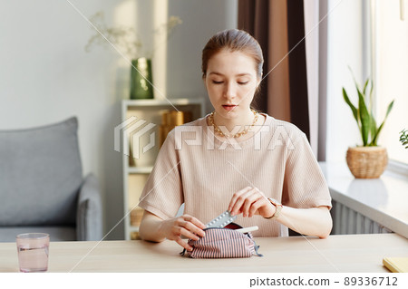 Young Woman Putting Pills in Travel Bag 89336712