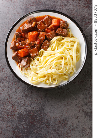 Daube Provencal classic French stew beef is slow simmered to tenderness served with noodles closeup in the plate. Vertical top view Daube Provencal classic French stew beef is slow simmered to tenderness served with noodles closeup in the plate. Vertical top view 89337078