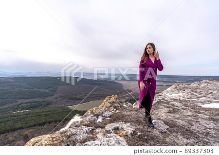 A beautiful woman stands on a high place with an amazing view of the mountains and the gorge. The concept of tourism, travel. 89337303