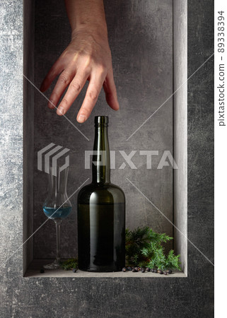 Hand reach for a vintage bottle of gin. Hand reach for a vintage bottle of gin. 89338394