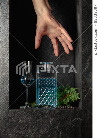 Hand reach for a decanter of gin. 89338397