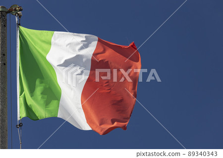 Italian flag blowing in the wind in the blue sky 89340343