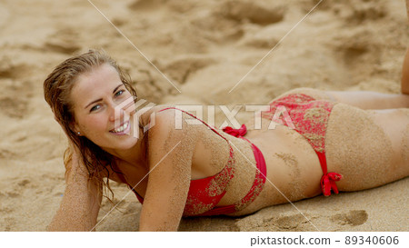 Sexy woman in a bikini relaxes on a sandy beach at the ocean Sexy woman in a bikini relaxes on a sandy beach at the ocean 89340606
