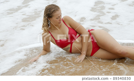 Sexy woman in a bikini relaxes on a sandy beach at the ocean Sexy woman in a bikini relaxes on a sandy beach at the ocean 89340830