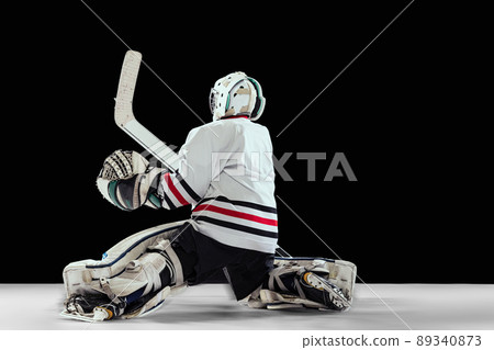 Dynamic portrait of teen boy, hockey player in motion, training isolated on black studio background. Professional goalkeeper Dynamic portrait of teen boy, hockey player in motion, training isolated on black studio background. Professional goalkeeper 89340873