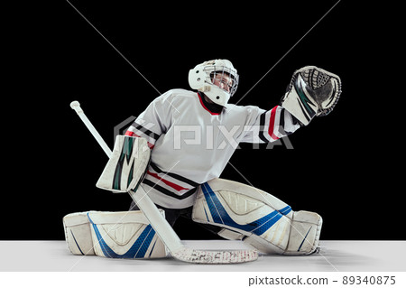 Dynamic portrait of teen boy, hockey player, goalkeeper catching puck with special glove isolated over black studio background Dynamic portrait of teen boy, hockey player, goalkeeper catching puck with special glove isolated over black studio background 89340875