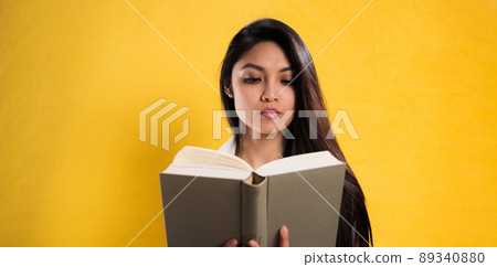 Young woman reads a book against a neutral background 89340880