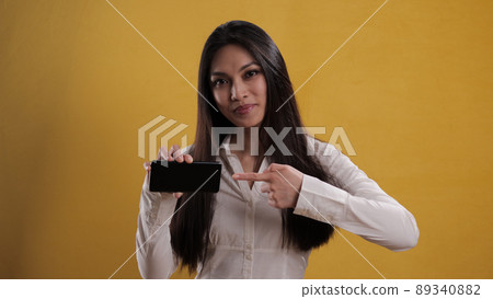 Young pretty woman points to a smartphone 89340882