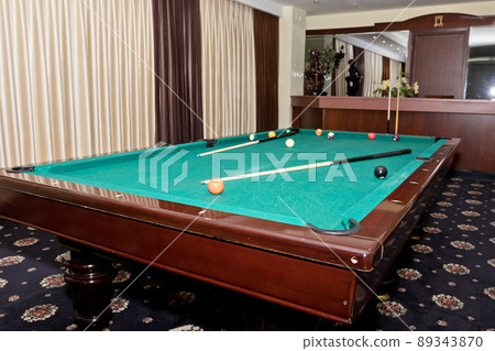 Worn pool table with a cue and balls in the great hall of the guests 89343870