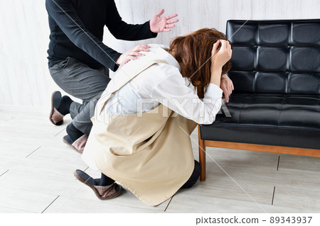 A husband who holds his head and calls out to his wife who has collapsed 89343937
