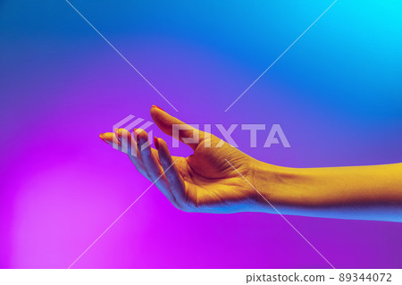 Studio shot of aethentic human hand isolated on gradient purple-blue background in neon light. Concept of human relation, community, togetherness Studio shot of aethentic human hand isolated on gradient purple-blue background in neon light. Concept of human relation, community, togetherness 89344072