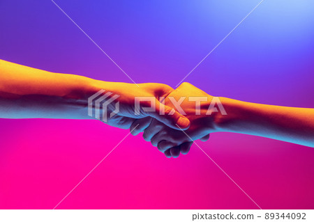Handshake. Male and female hands touching each other on gradient blue and pink background in neon. Concept of human rights, social issues, gathering. 89344092